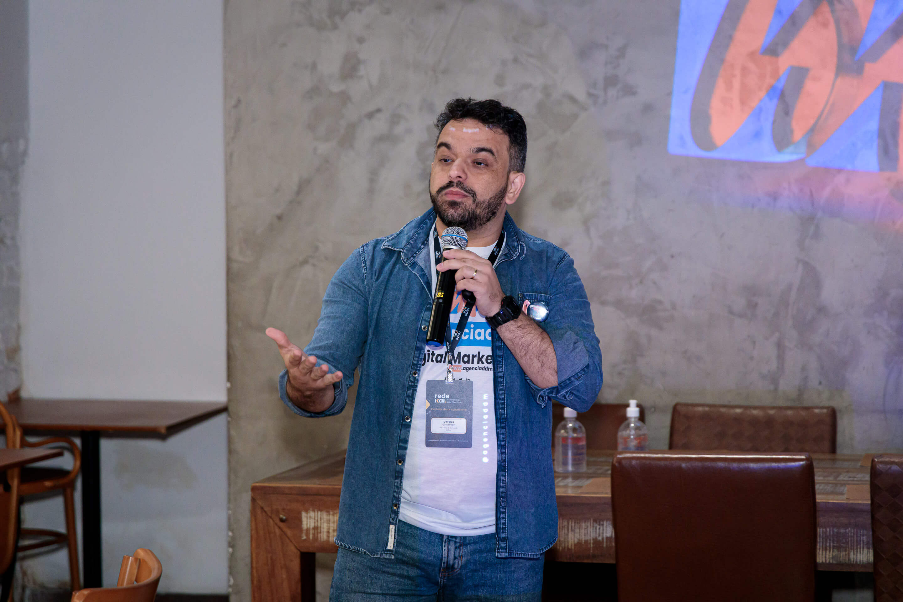 Douglas Oliveira palestrando com logo DDM ao fundo